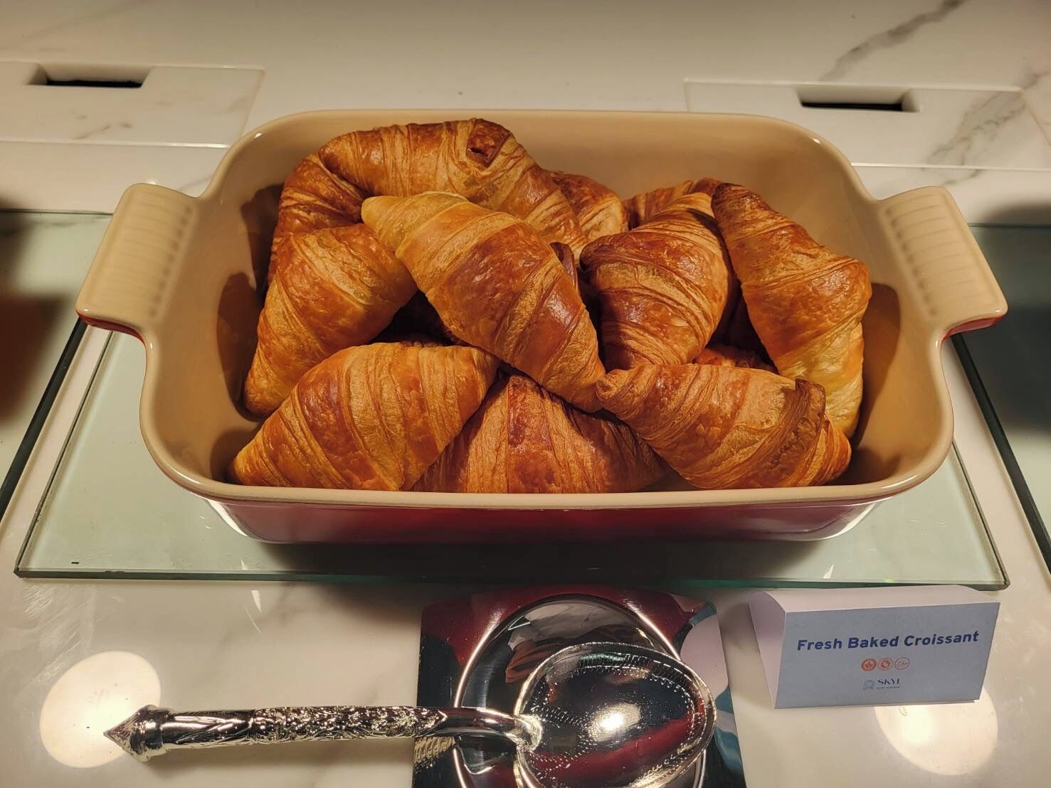 A display of fresh baked croissants in a beige ceramic dish.