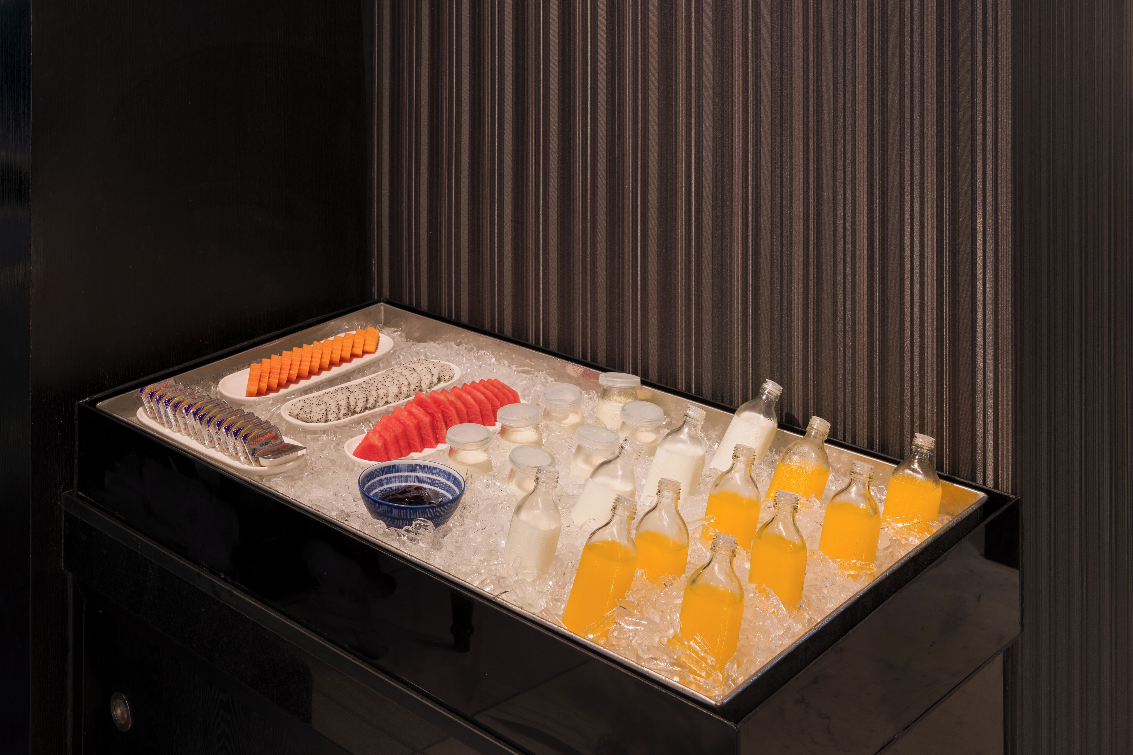 A buffet with various food items and beverages on a black countertop.