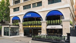 Un hotel con fachada moderna, que presenta un llamativo letrero 'MOSA' y un letrero 'Sky Cafe'.