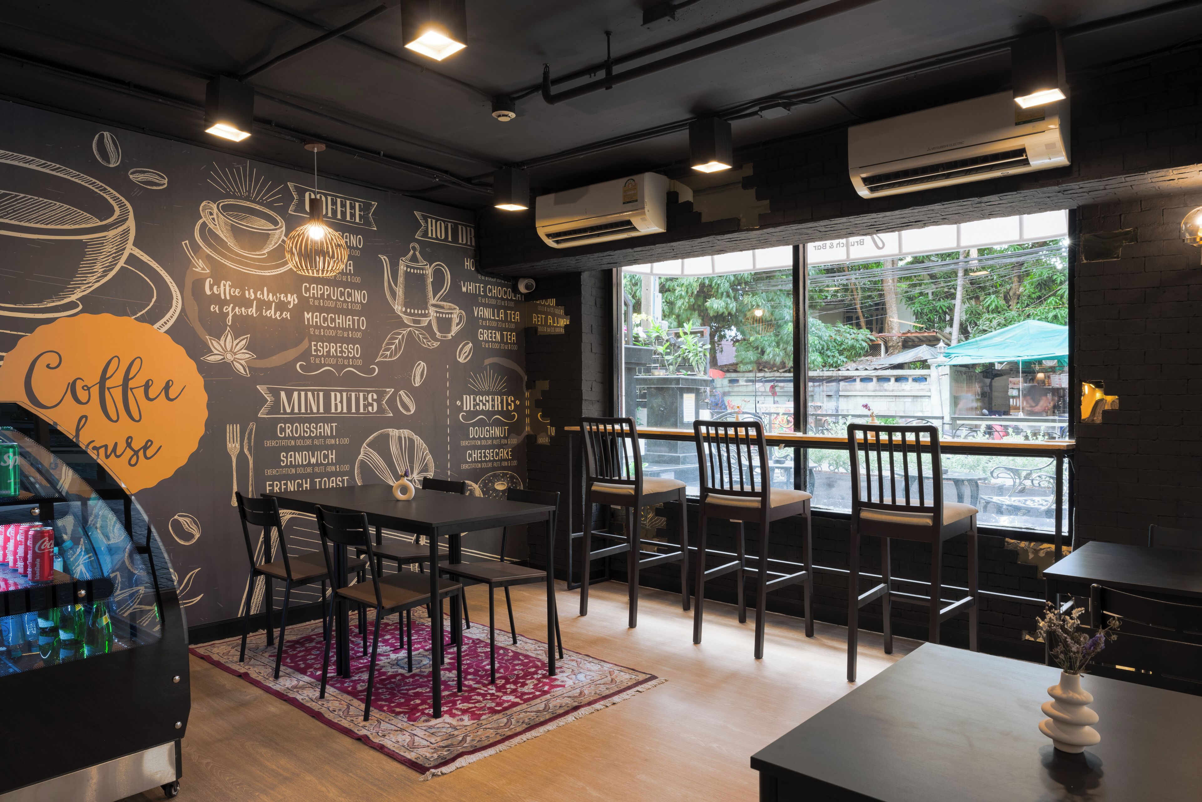 A coffee lounge with tables, chairs, and a chalkboard wall listing coffee drinks.