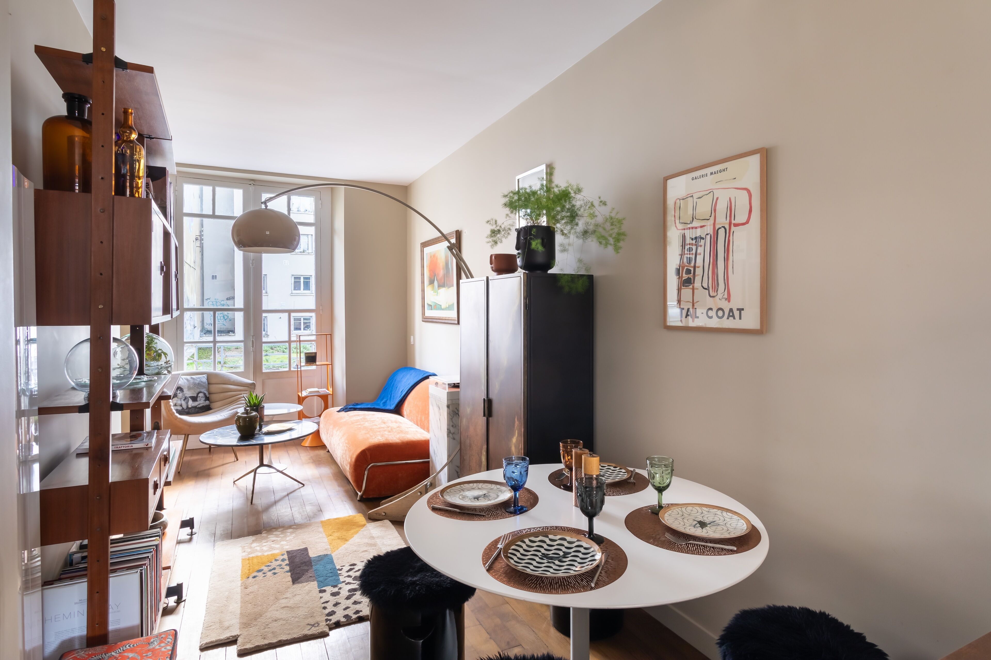 Un salon moderne avec une table à manger ronde, un canapé et une bibliothèque.