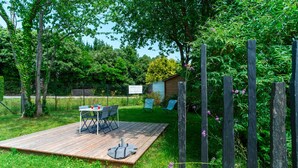A wooden deck with a table and chairs, surrounded by a wooden fence and greenery. - Le Haut du Nelud - Appt dans maison avec jardin (Locmariaquer)