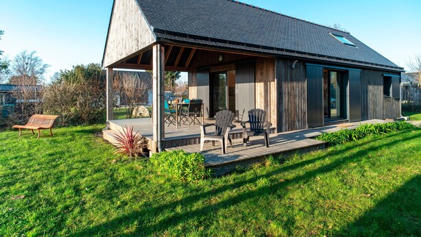 Una casa moderna con portico coperto, facciata in legno e un piccolo spazio attrezzato con veranda.
