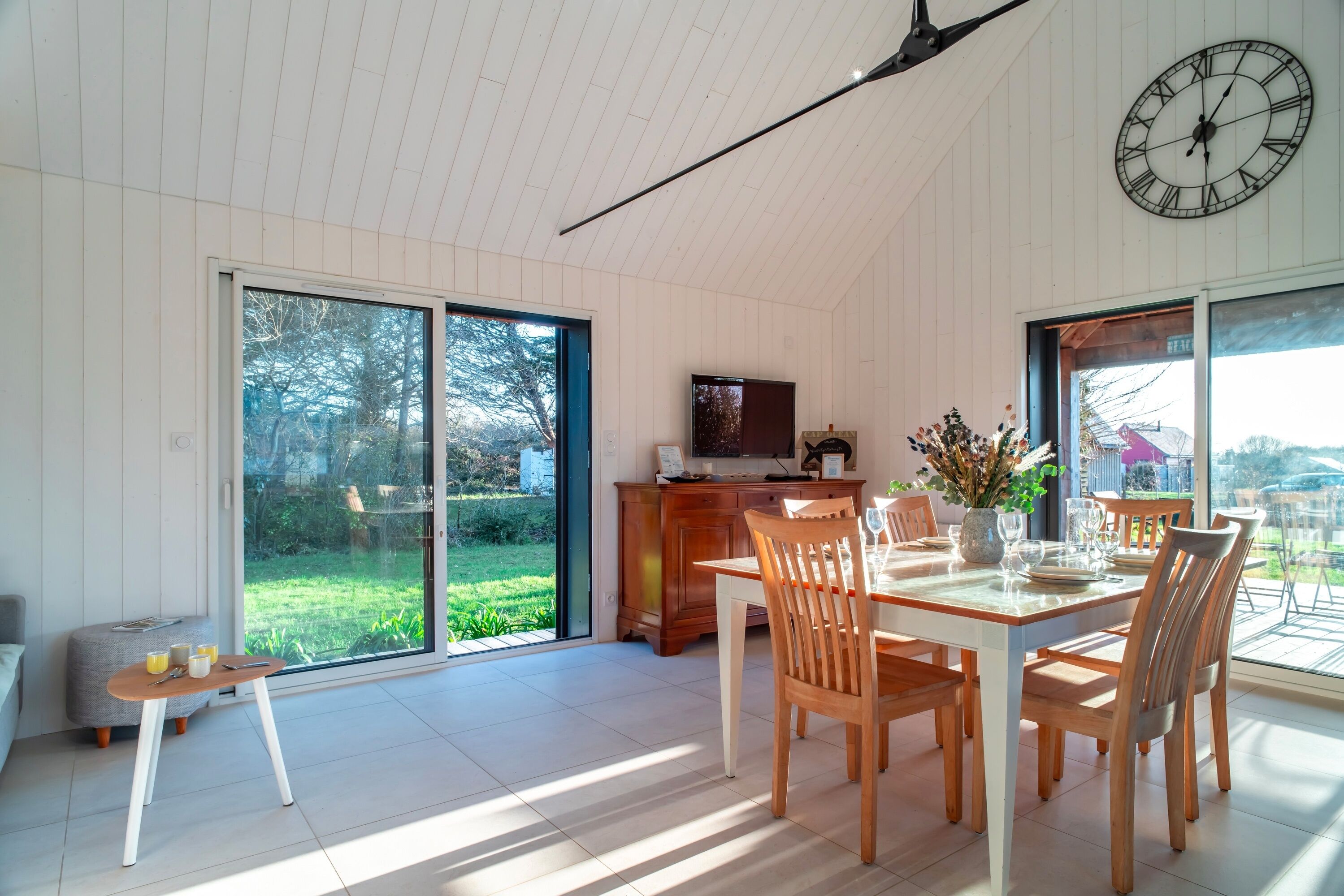 A spacious dining area with a large table and chairs, a wooden cabinet, and a television.