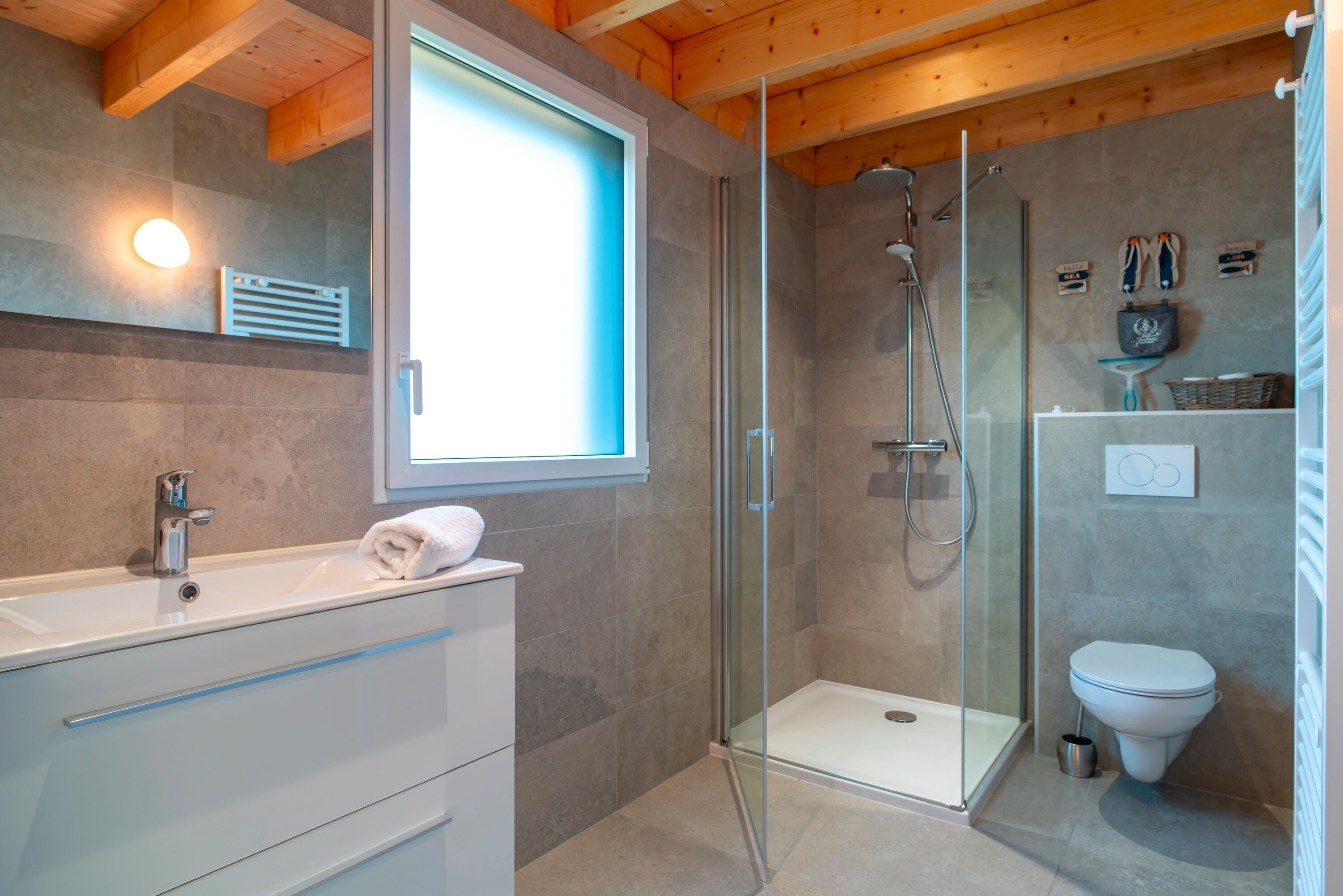 A modern bathroom with a glass-enclosed shower, a white sink with a towel, and a toilet.
