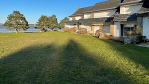 Ein zweistöckiges Haus mit gepflegtem Rasen und Blick auf das Wasser.