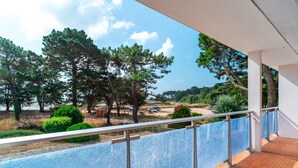 Ein Balkon mit Blick auf einen Parkplatz, Bäume und einen klaren Himmel.