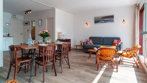 Ein modernes Wohnzimmer mit Essbereich, einer Couch und Korbstühlen.