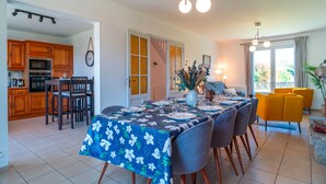 A dining area with a table set for four, wooden cabinets, a staircase, and a view of the outdoors.