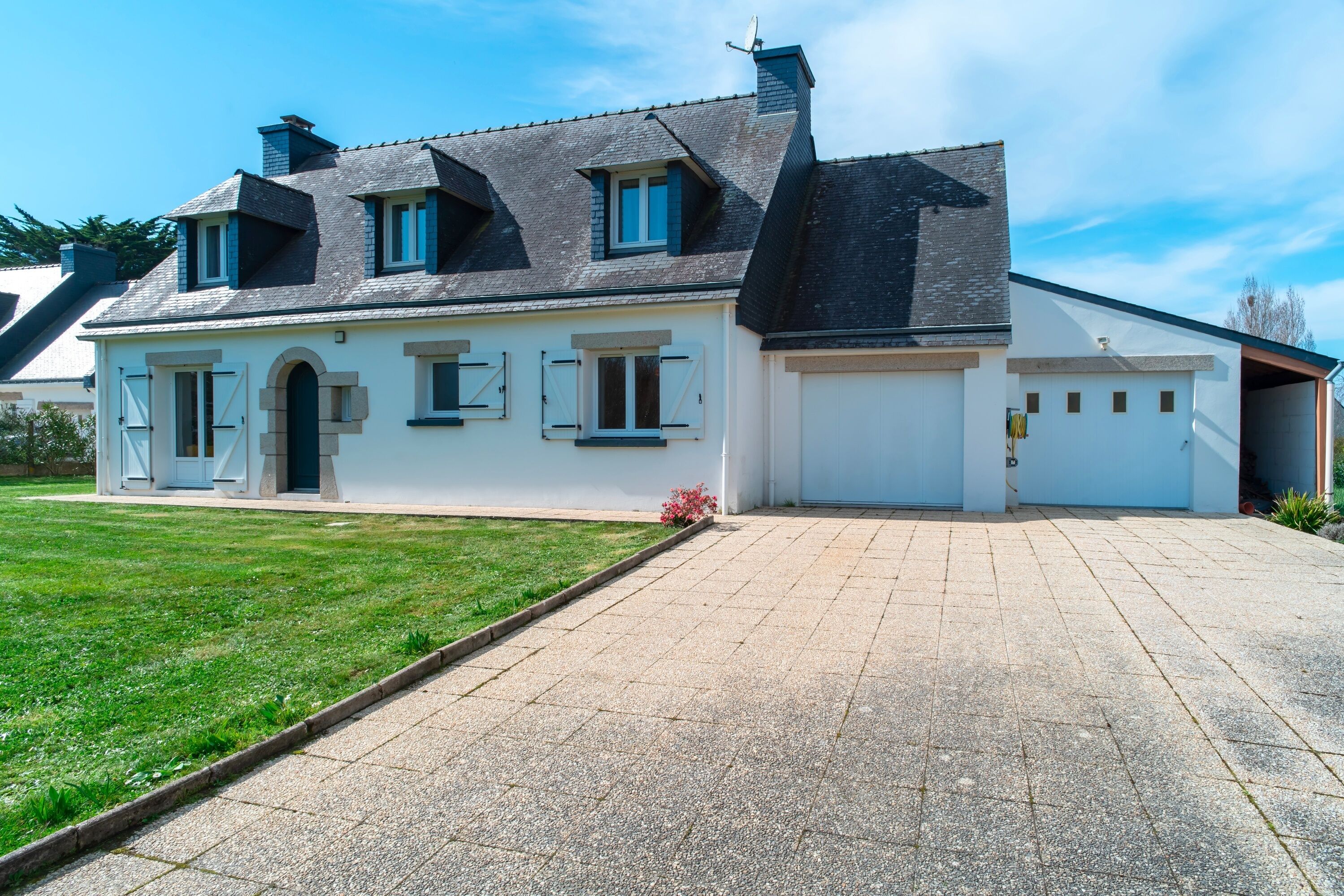 Ein zweistöckiges Haus mit Garage, Rasen und blauem Himmel.