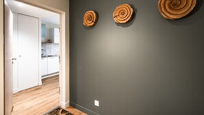 A hallway with a dark gray wall, a wooden floor, and three wooden wall decorations. - Villa du Port 2 - Appt vue port (La Trinite-sur-Mer)