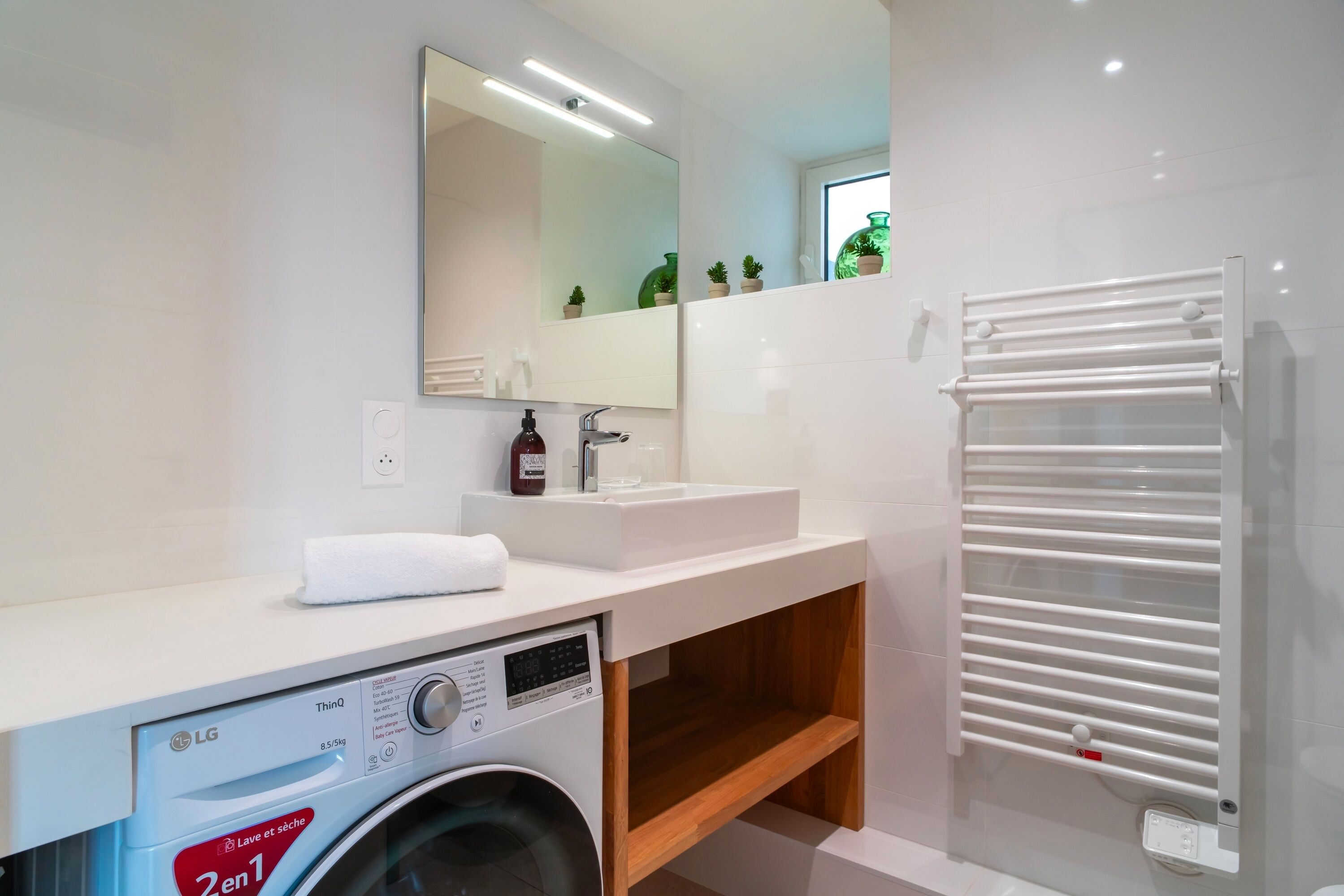 Een moderne badkamer met een wasmachine, een wastafel en een handdoekhouder.