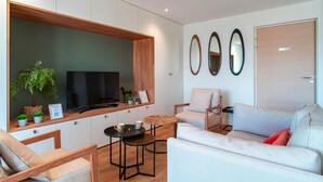 A modern living room with a TV, seating, and decorative mirrors. - Villa du Port 2 - Appt vue port (La Trinite-sur-Mer)