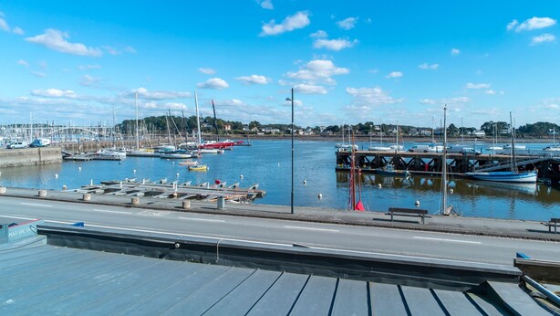A marina with boats docked, a road in the foreground, and a clear blue sky. - Villa du Port 2 - Appt vue port (La Trinite-sur-Mer)