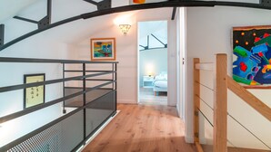 A modern interior with a staircase, a sign reading "ATTENTION!", and a painting on the wall. - L'Atelier Port Fétan - Vue mer (Locmariaquer)
