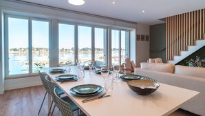 A dining area with a view of a marina, a staircase, and a sofa. - Villa du Port 6 - Sublime appt vue vieux port (La Trinite-sur-Mer)