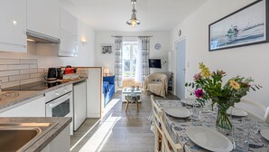 Una cocina moderna con comedor, televisor montado en la pared y ventana con cortinas.