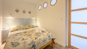 Un dormitorio con cama, mesita de noche, lámpara de pared y puerta con panel de vidrio esmerilado.