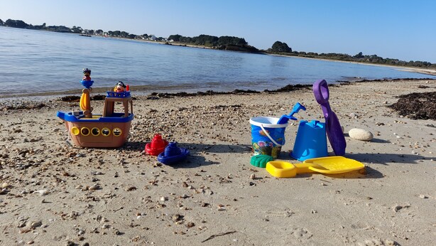 Una playa arenosa con un barco de juguete y diversos juegos de playa.
