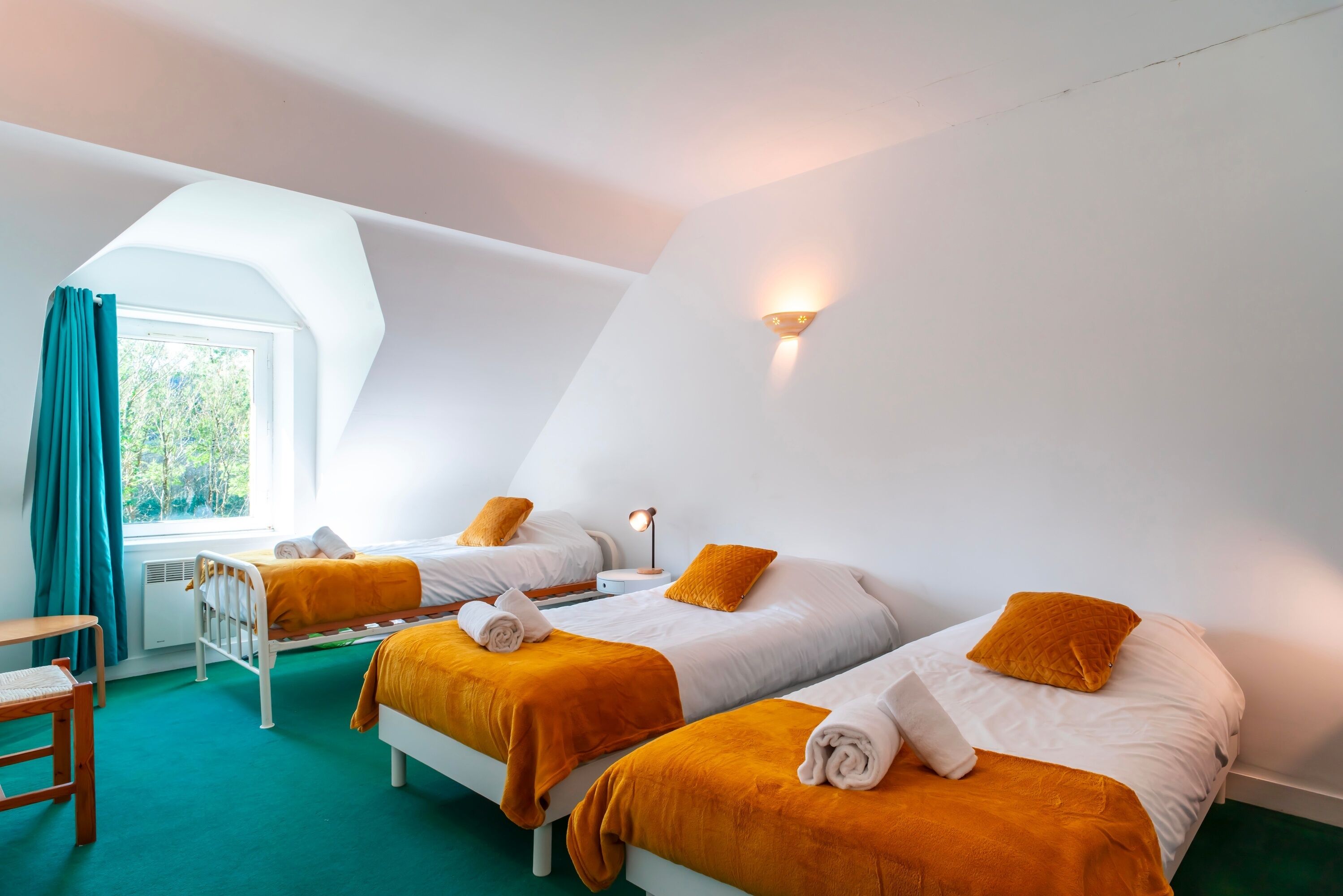 A room with two beds, a desk, and a window with curtains.