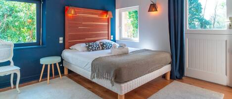 A bedroom with a bed, a chair, a window, and a radiator.