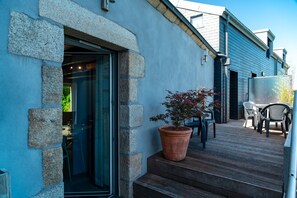 A stone exterior with a wooden deck, a potted plant, and outdoor furniture. - L'abri de Port Fétan - Vue mer (Locmariaquer)