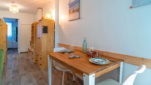 Una mesa de madera con sillas, una botella y vasos sobre la mesa.