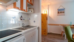 Una cocina compacta con gabinetes blancos, una encimera negra y un armario de madera sobre el fregadero.