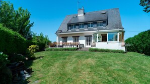 A large house with a sloped roof, a covered porch, and a well-maintained lawn.