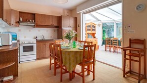A kitchen with wooden cabinets, a white stove, and a dining area with a table set for four.