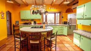 Une cuisine dotée d’un îlot central, de meubles de couleur verte et d’un sol carrelé.