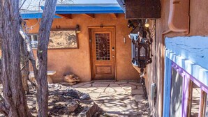 Un bâtiment rustique avec une porte en bois, un chemin en pierre et un toit bleu.