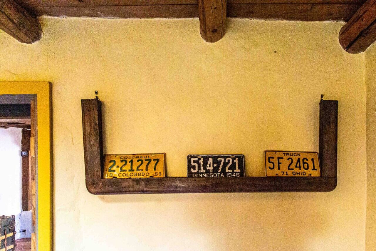 Una parete con tre targhe automobilistiche montate su un ripiano di legno.
