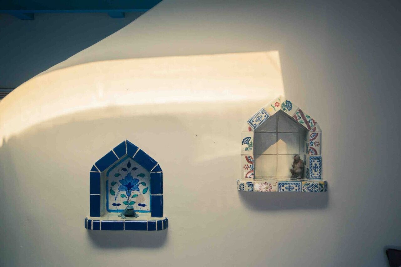 Two small, decorative windows with blue and white tiles, one with a floral design and the other with a patterned border.