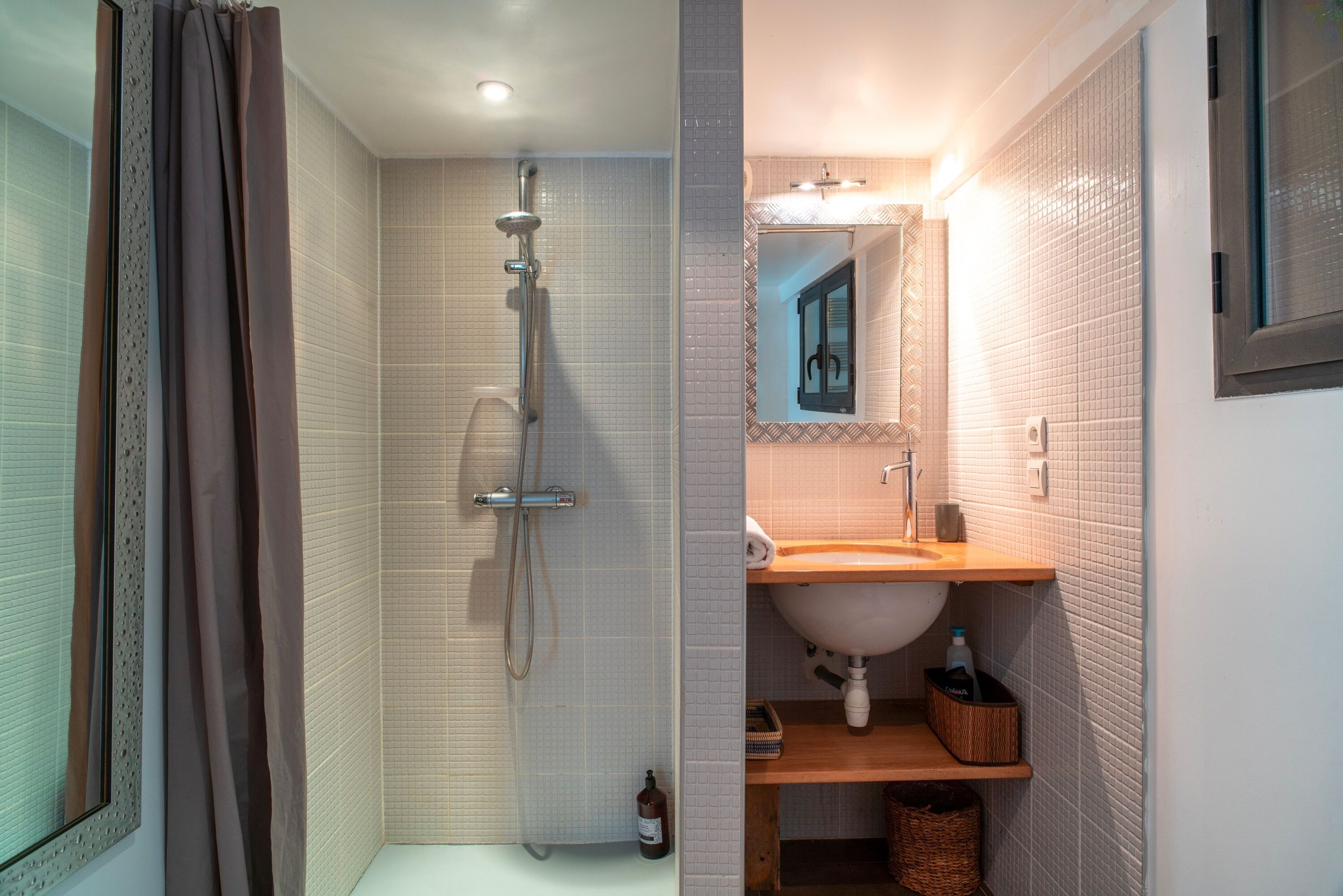 Un baño con ducha, lavamanos y espejo.