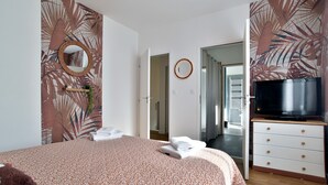 Ein Schlafzimmer mit einem Bett, einem Fernseher, einem Schminktisch und einem Spiegel.