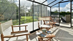 Ein Wintergarten mit Holzmöbeln und Blick auf einen Garten.
