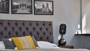 Un lit bien fait, avec une tête de lit capitonnée, une lampe de chevet et un banc au pied du lit.