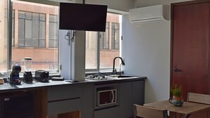 Une cuisine compacte équipée d’un four à micro-ondes encastré, d’un évier et d’une fenêtre donnant sur un immeuble.