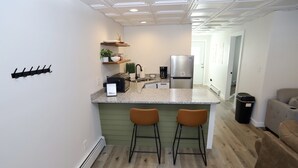 Een moderne keuken met een centraal eiland, barkrukken en een koelkast.