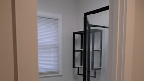 Een badkamer met toilet, een douchecabine van glas, een witte toiletrolhouder, en een raam met zonwering.