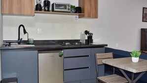 Une cuisine compacte équipée d’un lave-vaisselle, d’une machine à café, d’un grille-pain et d’un évier.