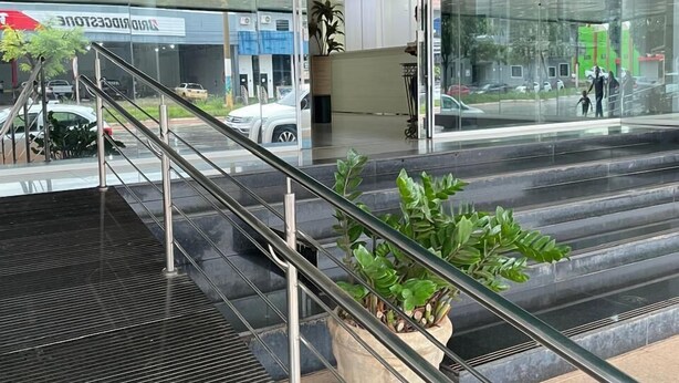 An indoor area with a staircase, glass walls, and a potted plant.