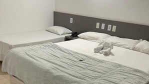 A hotel room with a large bed, a smaller bed, and a nightstand with a phone.