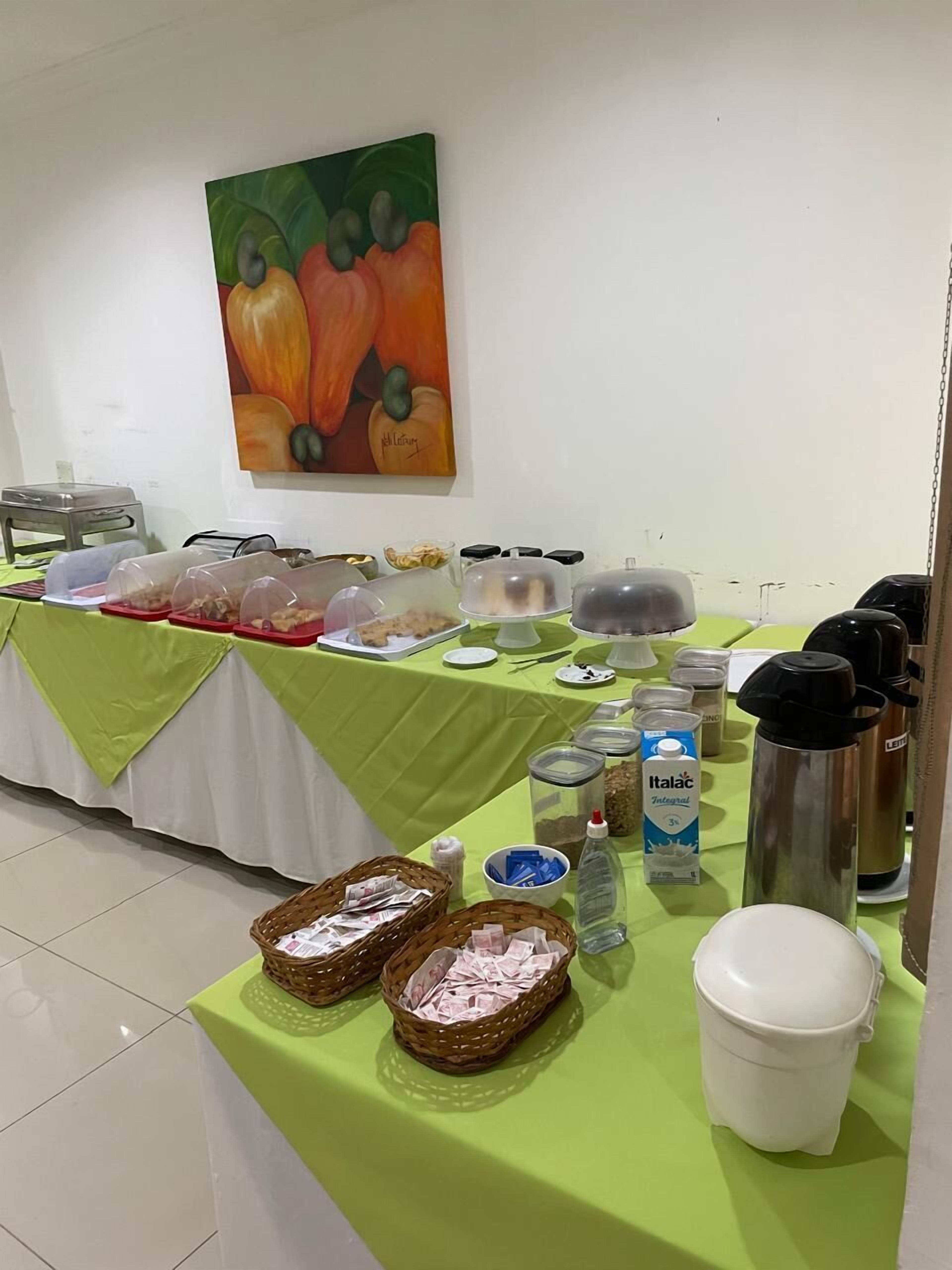 Un'area buffet con diversi cibi e contenitori, un quadro appeso al muro e un pavimento piastrellato.