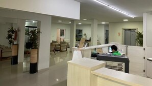 A modern office space with cubicles, a reception desk, and a seating area with chairs and a sofa.
