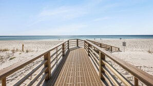 A wooden boardwalk leading to a beach with a clear sky.