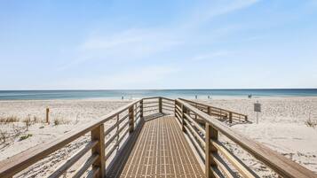 Un muelle de madera que conduce a una playa bajo un cielo despejado.
