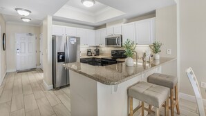 A modern kitchen with white cabinets, stainless steel appliances, and a granite countertop.