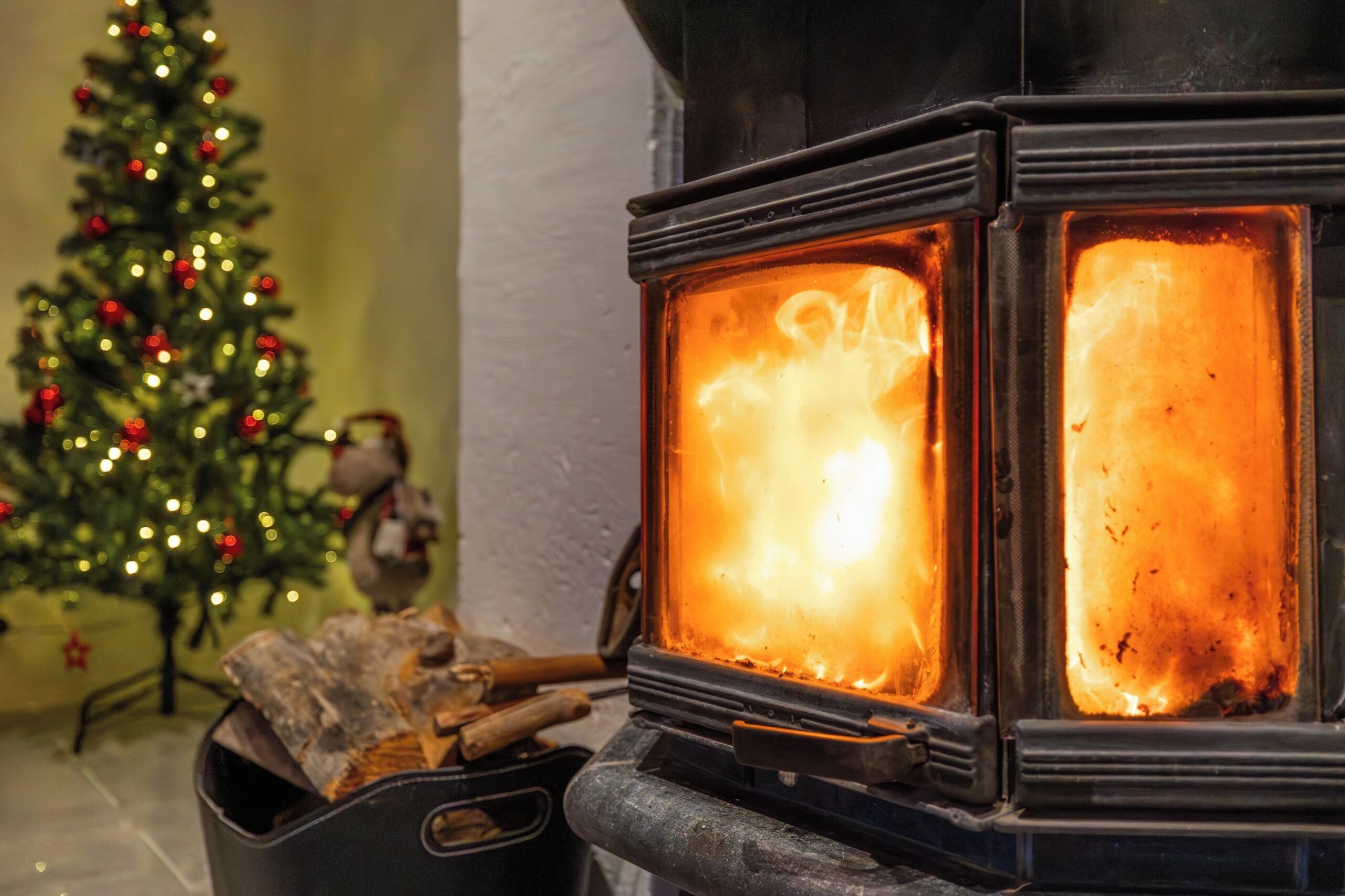 Un poêle à bois avec des flammes apparentes et des bûches disposées devant.